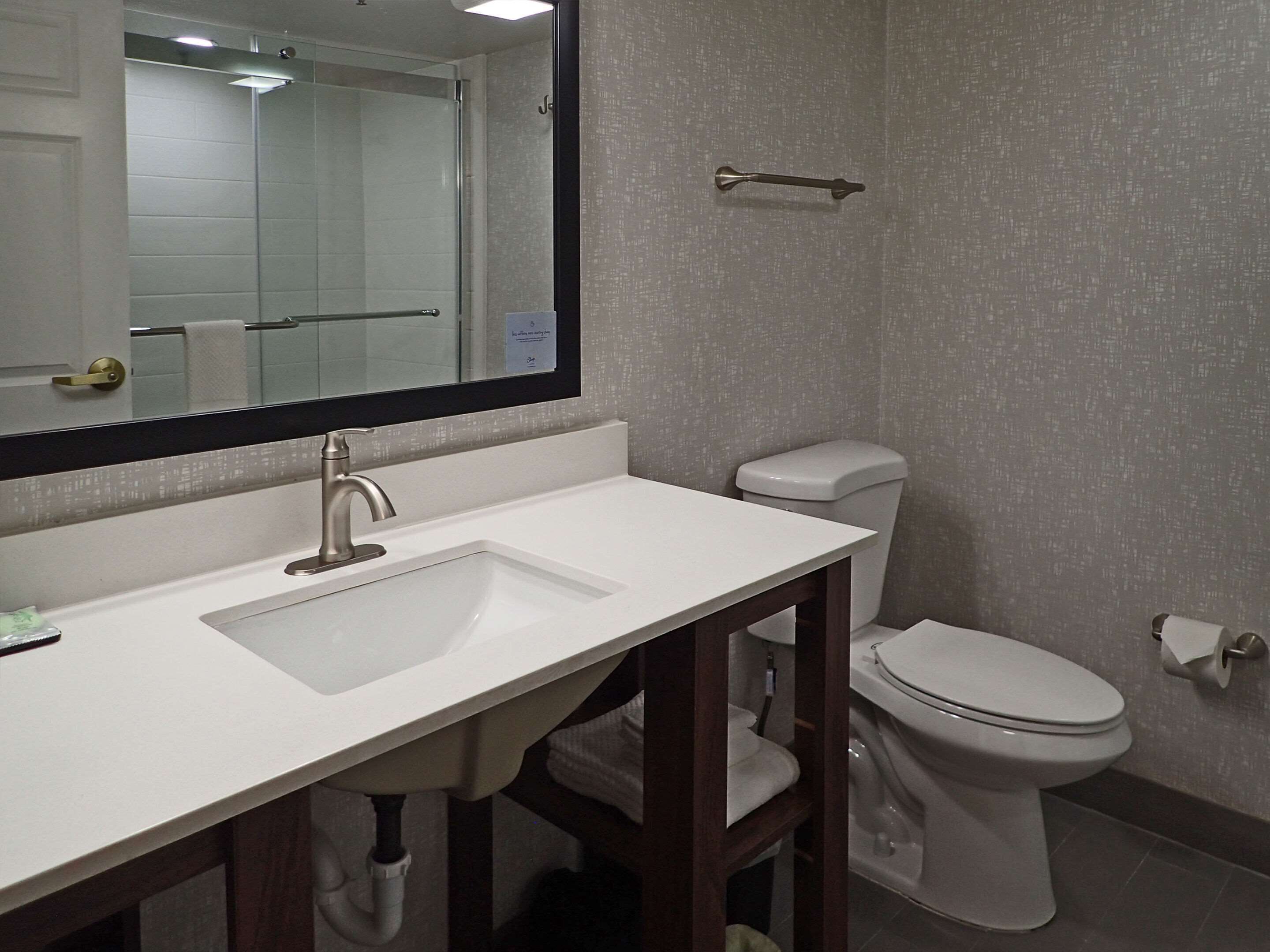 A bathroom with a white sink, a mirror, a toilet, and a towel rack.