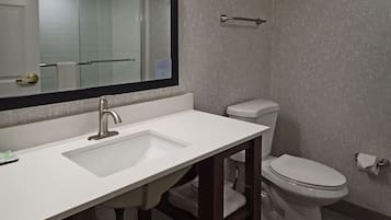 A bathroom with a white sink, a mirror, a toilet, and a towel rack.
