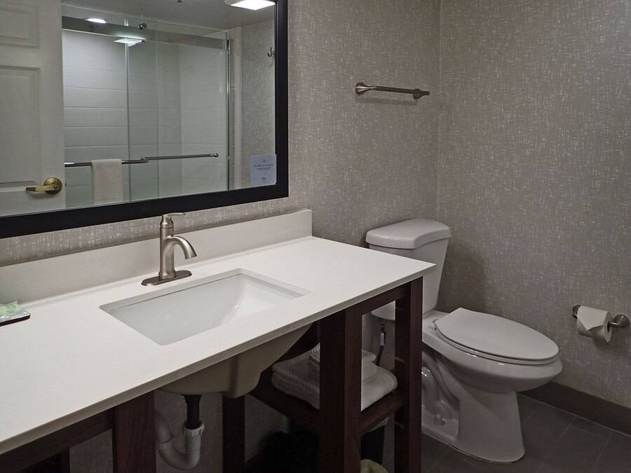 A bathroom with a white sink, a mirror, a toilet, and a towel rack.