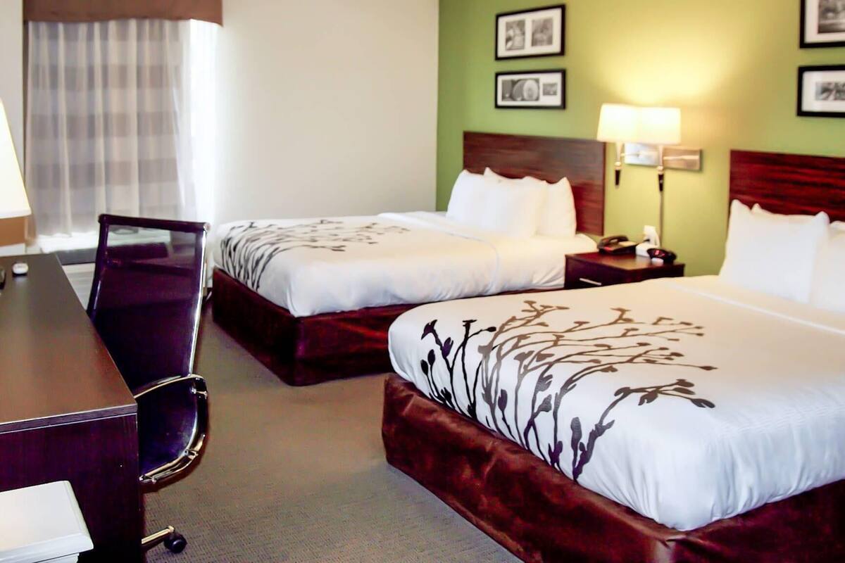 Ein Hotelzimmer mit zwei Betten, einem Schreibtisch und einem Stuhl.