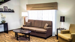 A living room with a sofa, a round coffee table, a side table with a lamp, and a chair. - Sleep Inn & Suites Stony Creek - Petersburg South (Stony Creek)