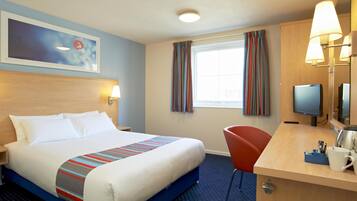 A hotel room with a bed, a desk, a chair, a television, and a window with curtains.