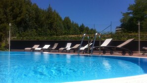 Una piscina con sillas de descanso y un cielo azul despejado.