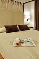 Cama bem arrumada com uma bandeja de itens de café da manhã, incluindo chá, biscoitos e geleia.