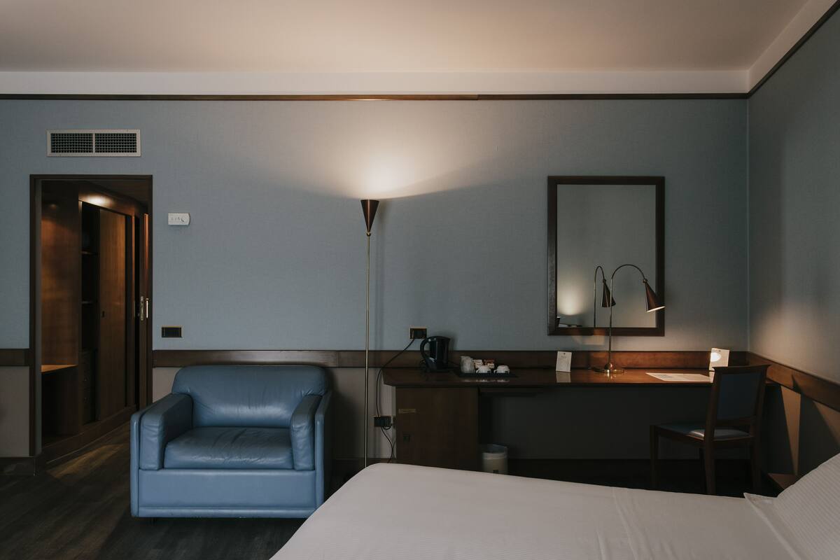 Une chambre d’hôtel comprenant un lit, un bureau avec une lampe, une chaise et une armoire.