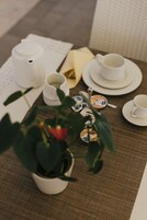 Una mesa dispuesta con vajilla blanca, una tetera y una planta en maceta.