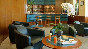 Un vestíbulo con asientos de cuero, una zona de bar con estantes llenos de botellas y una orquídea blanca grande.