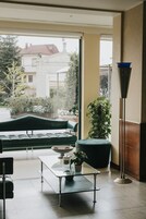 Uma sala de estar moderna com uma mesa de centro de vidro, um sofá verde e um vaso de planta.