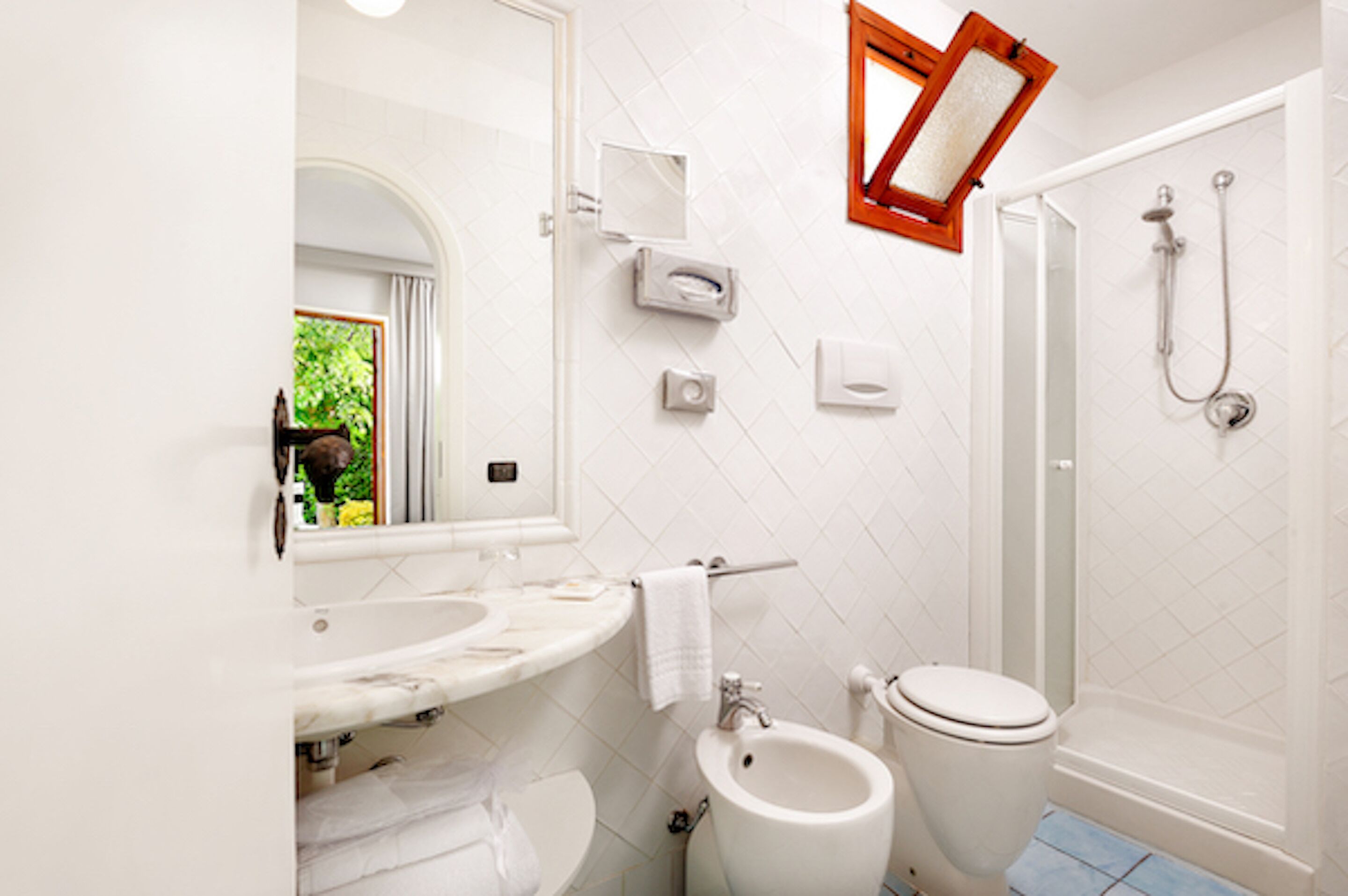 A bathroom with a sink, bidet, toilet, and shower.