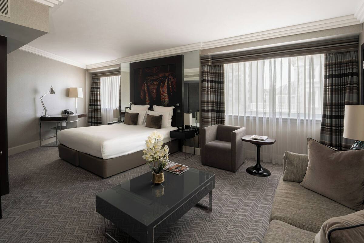 Ein modernes Hotelzimmer mit einem großen Bett, einem Schreibtisch, einem Stuhl, einem Couchtisch und einer Couch.