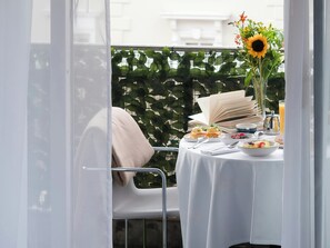 A balcony with a table set for breakfast, including plates of food, a book, and a vase with flowers. - The Lowndes London – A Jumeirah Partner Hotel (London)