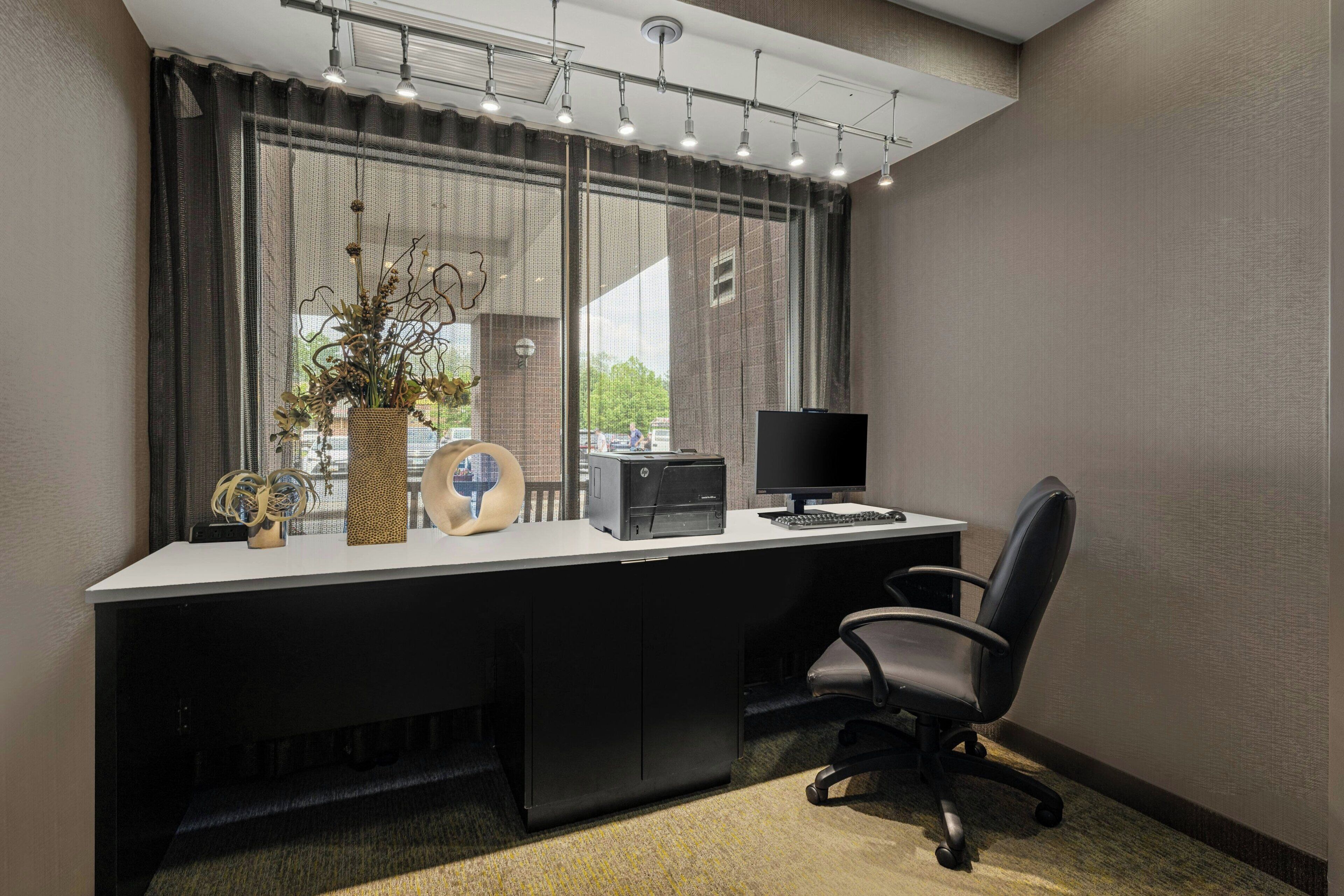 A modern office desk with a computer, a chair, and decorative items.