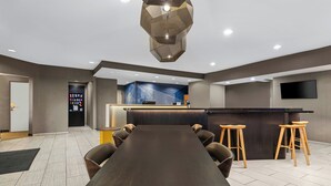 Een moderne vergaderruimte met een lange tafel, meerdere stoelen, een receptiebalie en een bar.