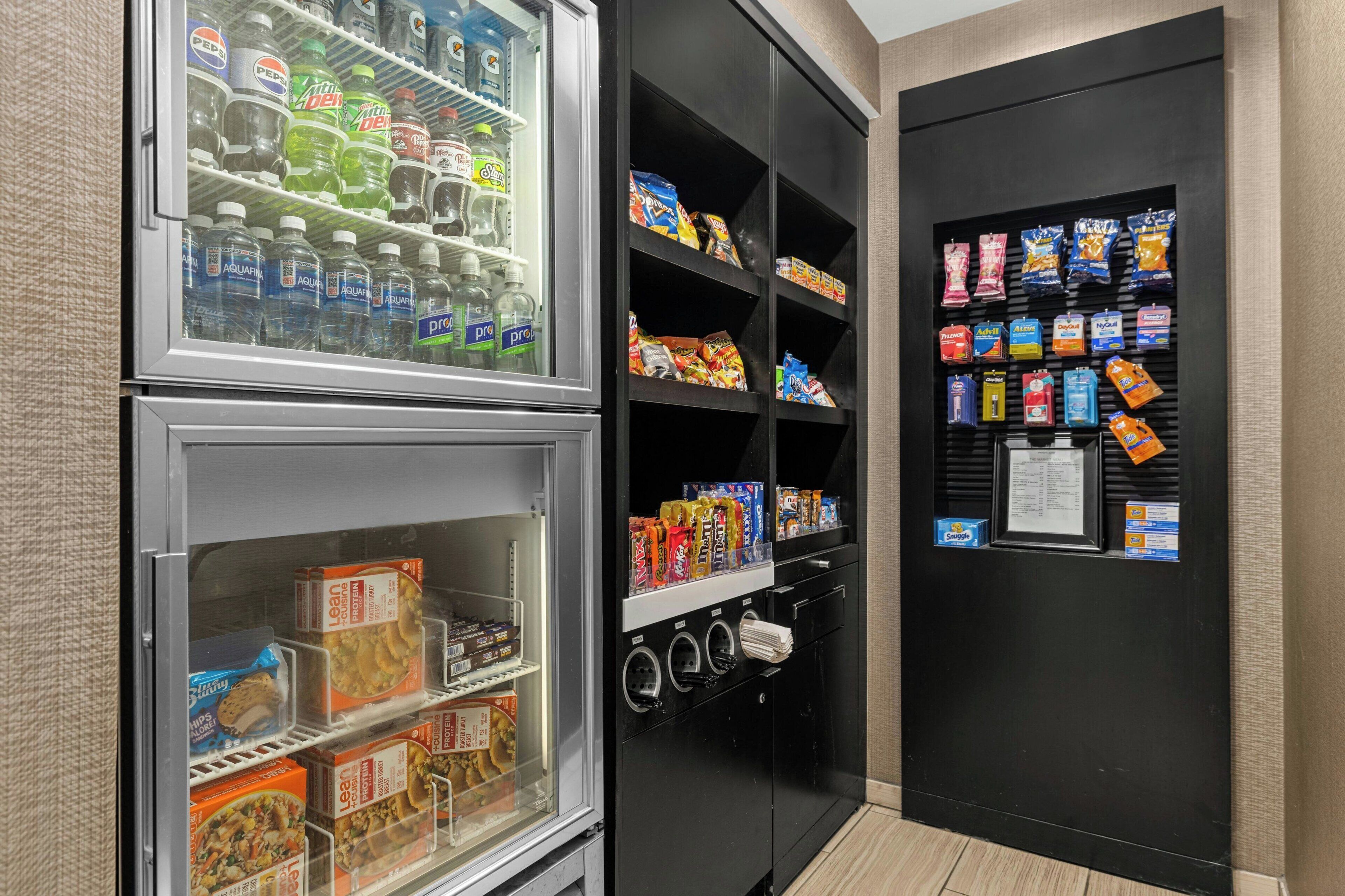 A vending machine with snacks and drinks, a refrigerated section with bottled water and soda, and a freezer with packaged food items.