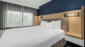Een moderne hotelkamer met een groot bed, een houten hoofdbord en een wand met een geometrisch patroon.