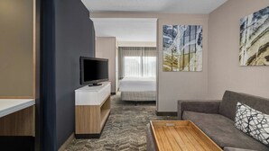 Een hotelkamer met een bed, een televisie, een bank en een klein tafeltje.