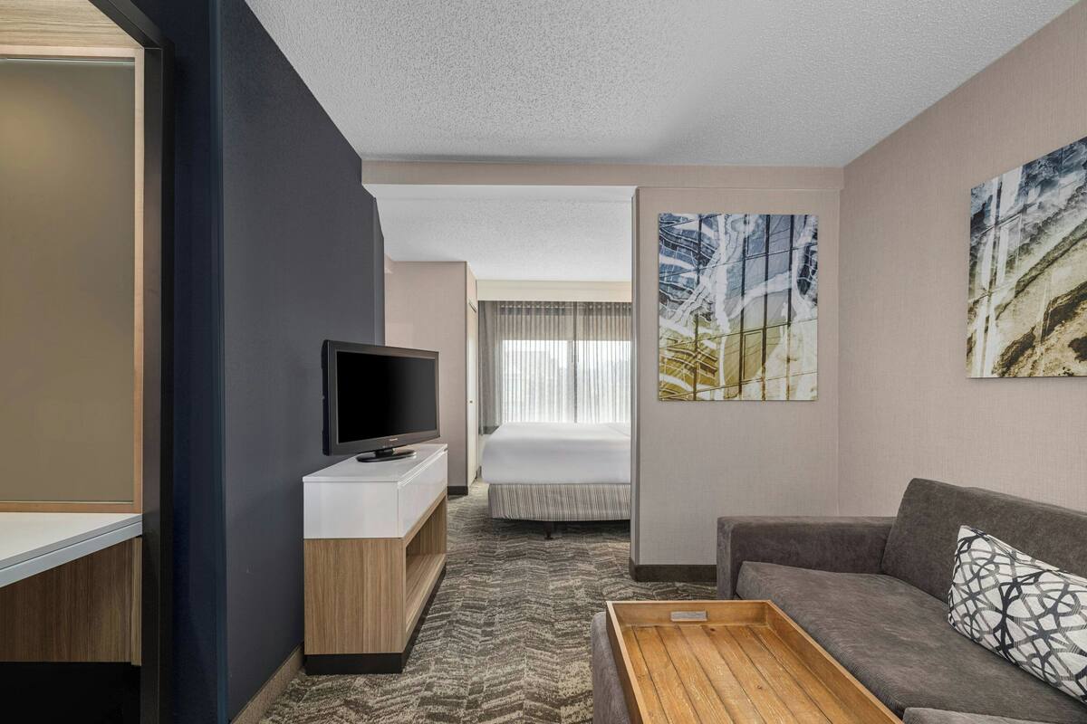 A hotel room with a bed, a TV, a sofa, and a small table.