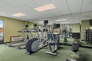 Un gimnasio con cintas de correr, elípticas y equipo de pesas.