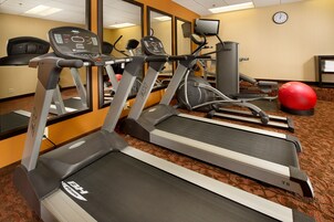 Un gimnasio con cintas de correr, una bicicleta estática y una pelota de ejercicios roja.