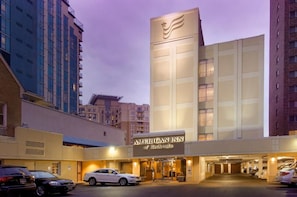 A hotel with a prominent sign, a parking area, and a building facade.
