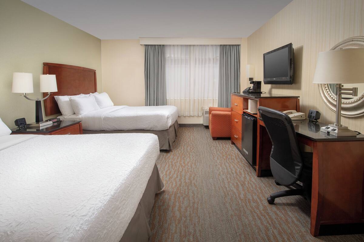 A hotel room with two beds, a desk with a computer, a TV, and a telephone.
