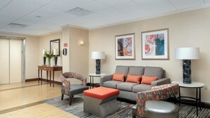 A hotel lobby with a sofa, chairs, a coffee table, and two lamps. - American Inn Of Bethesda (Bethesda)