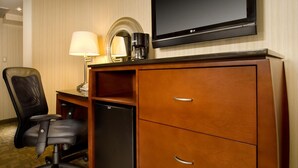 A hotel room with a wooden desk, a black office chair, a flat-screen TV, a coffee maker, and a refrigerator. - American Inn Of Bethesda (Bethesda)