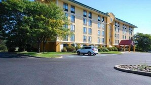 A multi-story hotel with a yellow facade, a covered parking area, and a car parked in front. - Quality Inn & Suites Bensalem (Bensalem)