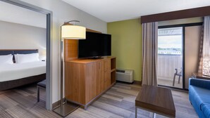 A hotel room with a bed, a TV on a wooden cabinet, a small table, a sofa, and a balcony with a view. - Holiday Inn Express Hotel & Suites Philadelphia – King of Prussia by IHG (King of Prussia)