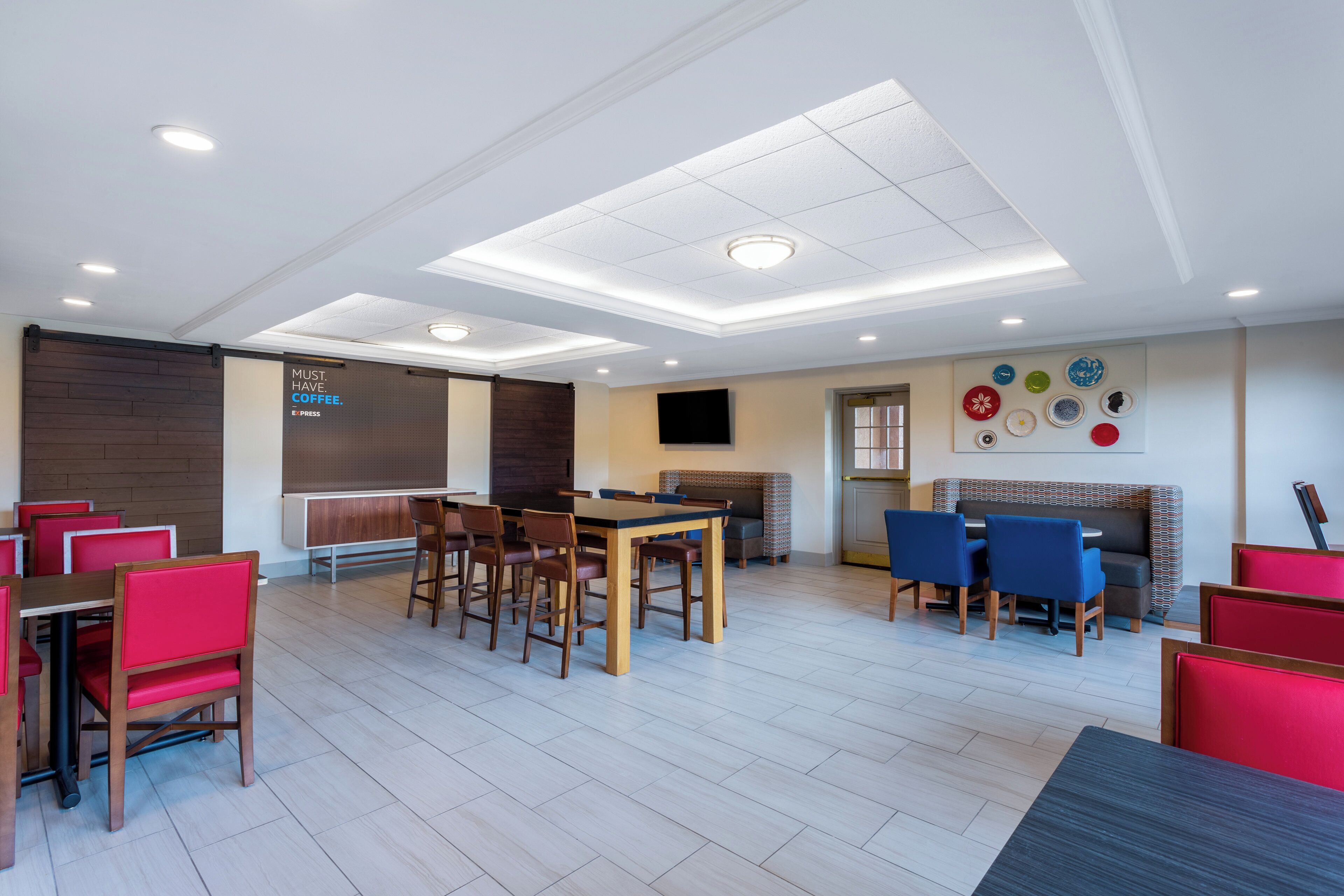 A modern hotel lobby with a dining area, seating arrangements, and a fireplace.