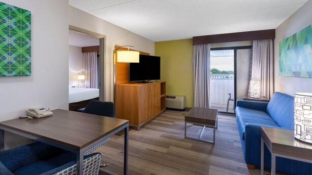 A hotel room with a bed, a TV on a wooden cabinet, a sofa, a table, and a chair. - Holiday Inn Express Hotel & Suites Philadelphia – King of Prussia by IHG (King of Prussia)
