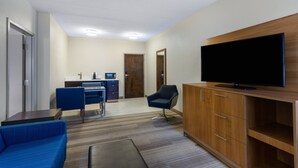 A modern hotel room with a flat-screen TV, a sofa, a desk with a chair, and a wooden cabinet. - Holiday Inn Express Hotel & Suites Philadelphia – King of Prussia by IHG (King of Prussia)