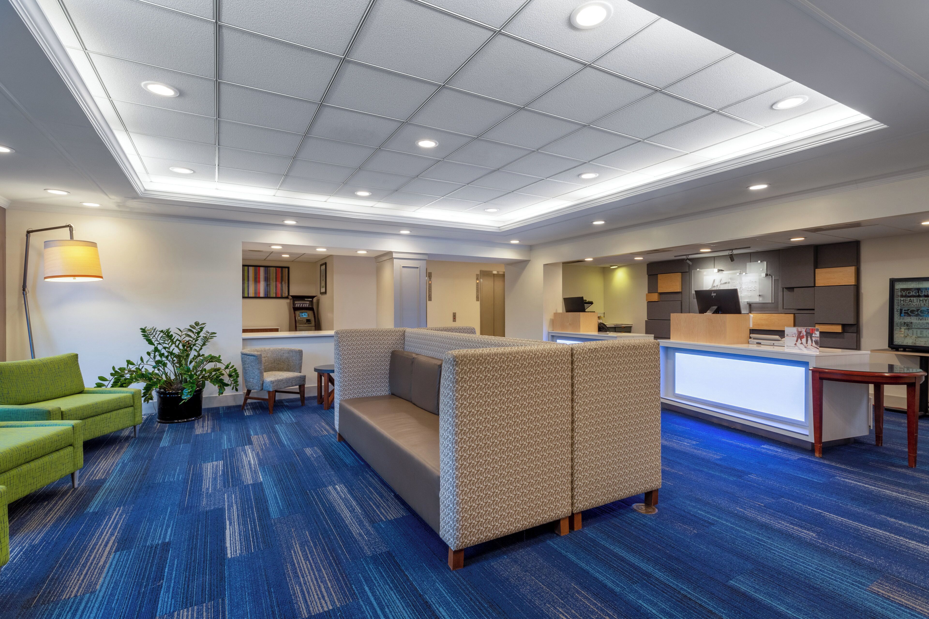 A hotel lobby with a reception desk, seating area, and a plant.