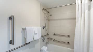 A bathroom with a bathtub, a shower, and a toilet. There are grab bars installed for safety.
