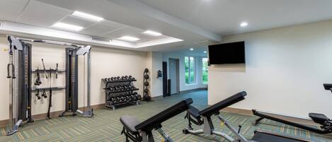 A gym with treadmills, weight machines, and dumbbells.