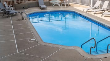 Una piscina al aire libre de temporada, sombrillas, tumbonas