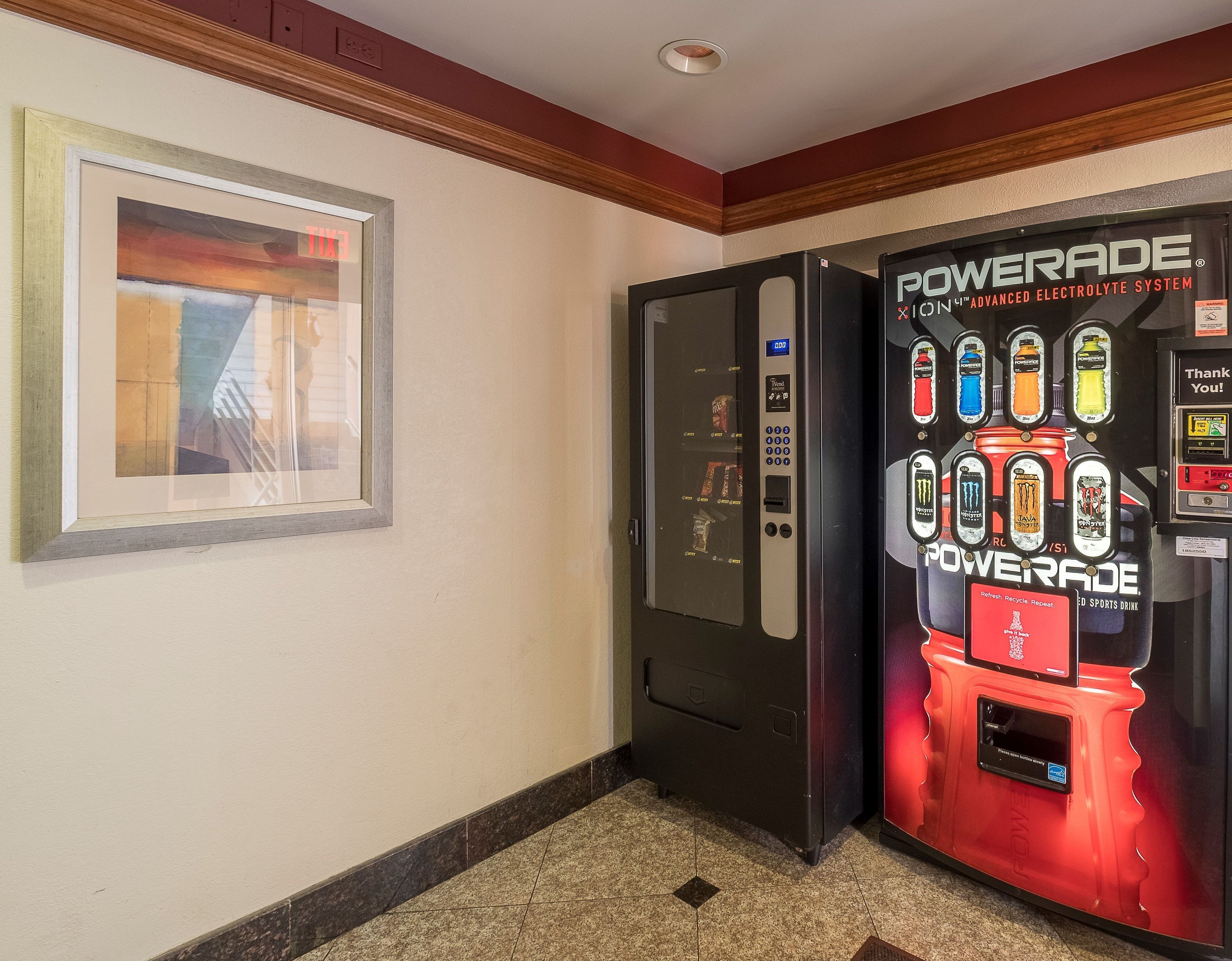 A hallway with a framed artwork on the left and a Powerade vending machine on the right.