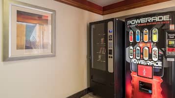 A hallway with a framed artwork on the left and a Powerade vending machine on the right.