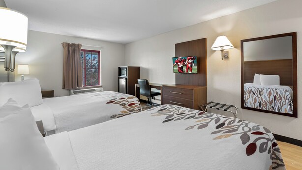 A hotel room with two beds, a desk, a chair, a television, and a mirror. - Red Roof Inn Lancaster (Lancaster)