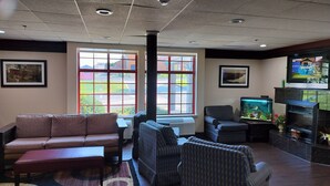 A living room with a sofa, armchairs, a coffee table, a TV, and a fish tank. - Red Roof Inn Lancaster (Lancaster)