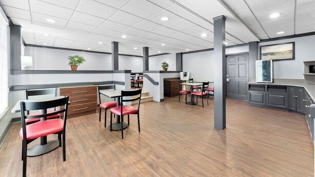 A spacious indoor area with multiple tables and chairs, a kitchen area, and a staircase. - Red Roof Inn Lancaster (Lancaster)