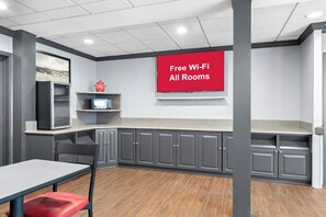 A modern kitchen with grey cabinets, a red sign stating "Free Wi-Fi All Rooms," and a microwave on the countertop. - Red Roof Inn Lancaster (Lancaster)