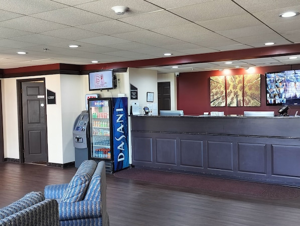 A reception area with a counter, a vending machine, a seating area, and a television screen.