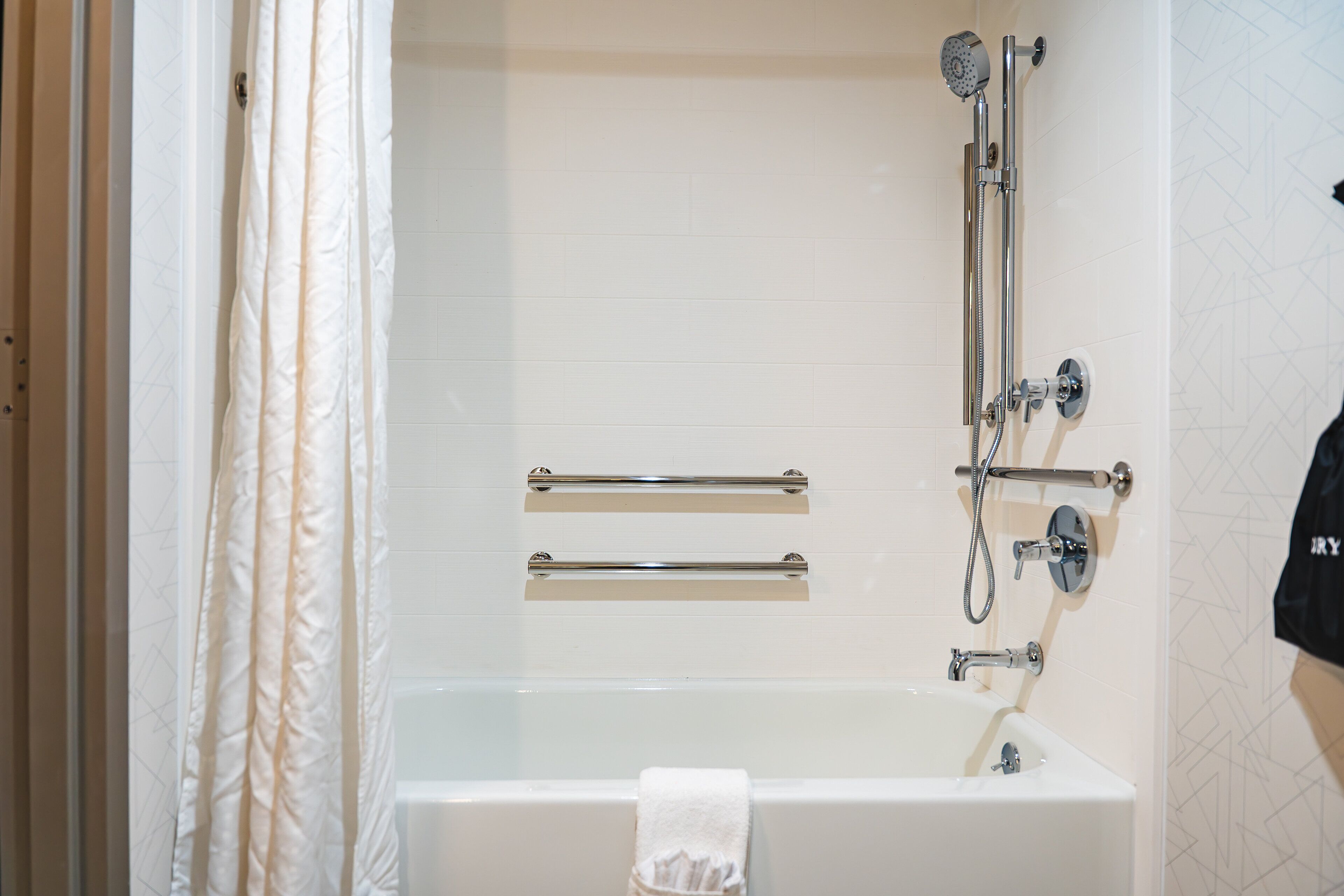 Un baño con bañera, ducha y dos barras para toallas.