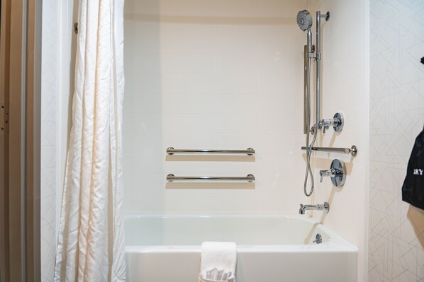 Une salle de bain équipée d’une baignoire, d’une douche et de deux porte-serviettes.