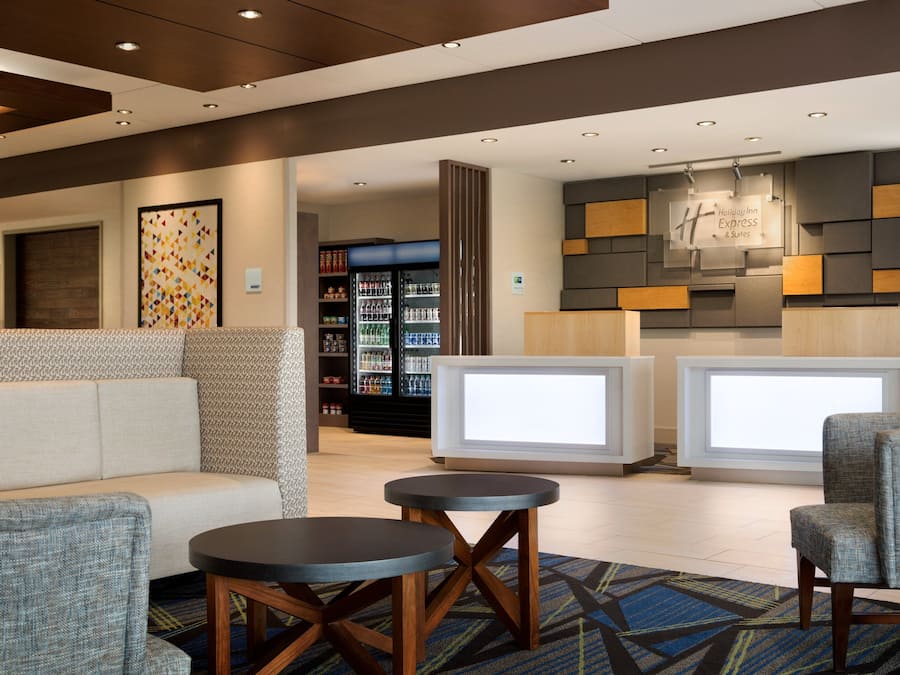 A lobby area with seating, a reception desk, and a refrigerator stocked with beverages.