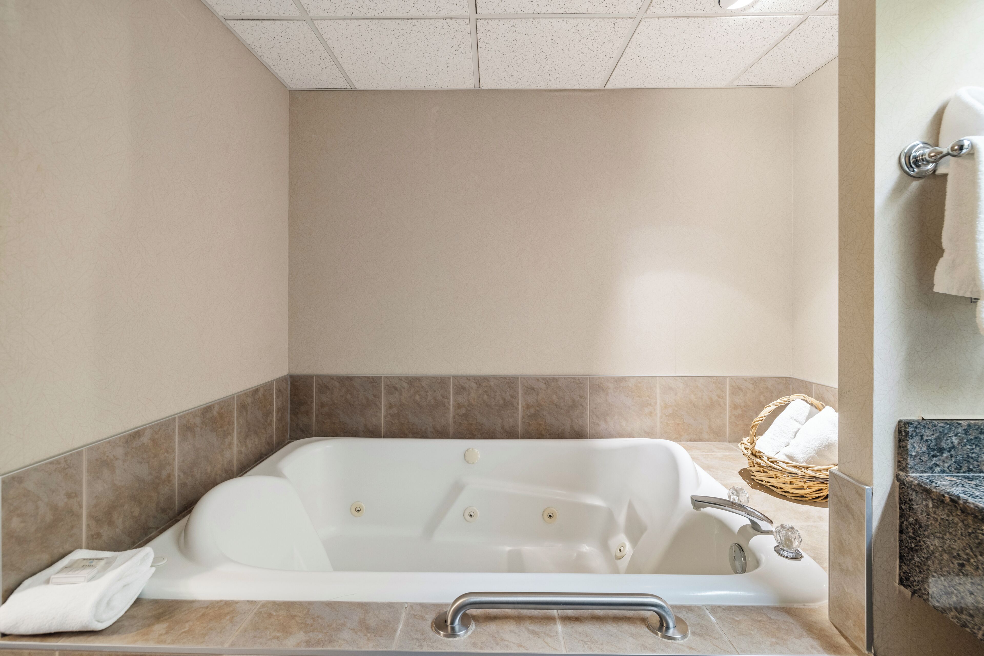 Un baño con bañera, una toalla y una cesta de mimbre.