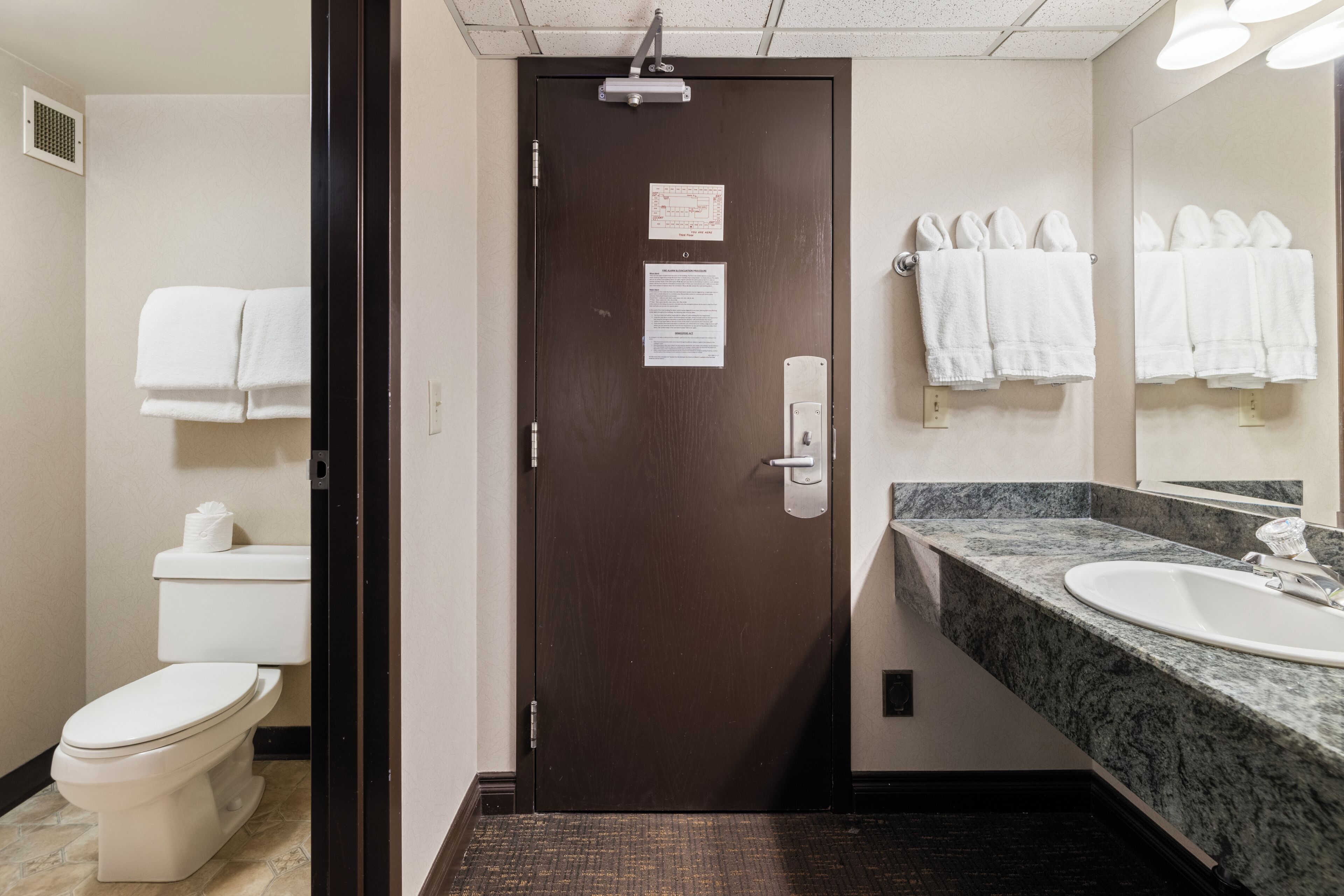 A hotel bathroom with a toilet, sink, and towel rack.