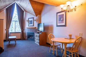 A cozy room with a fireplace, a television, a dining table with chairs, and a chandelier.