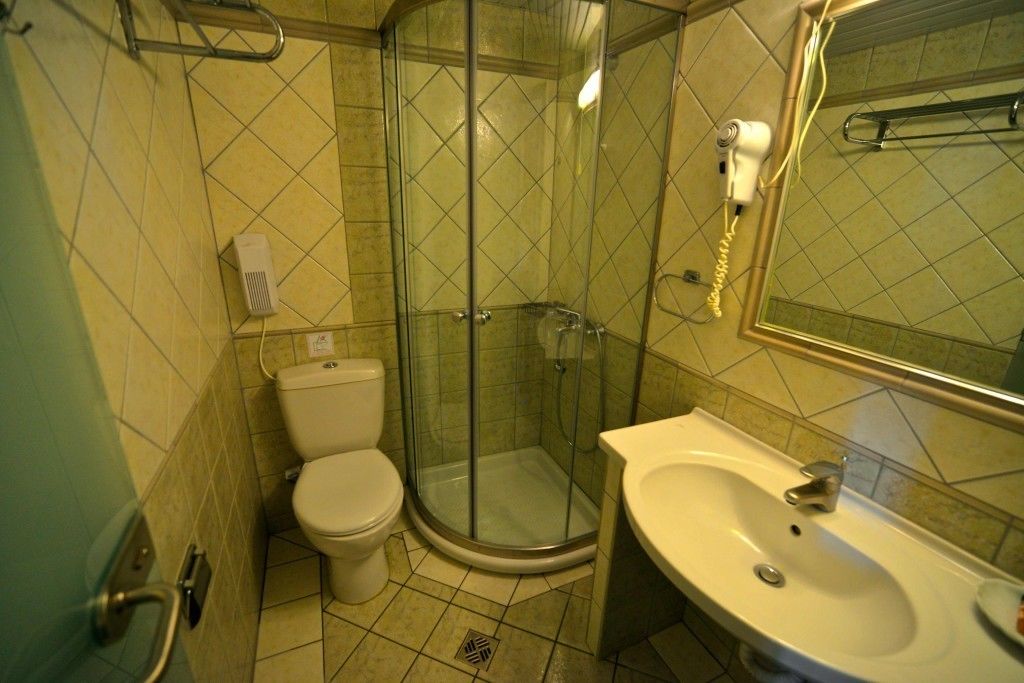 A bathroom with a glass-enclosed shower, a toilet, and a sink.